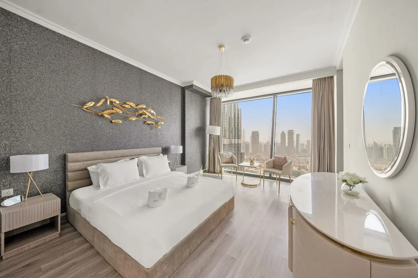 A bedroom with a large bed, seating by the window, and a city view.