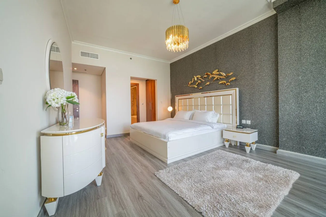 A bedroom with a white bed, bedside table, and rug.