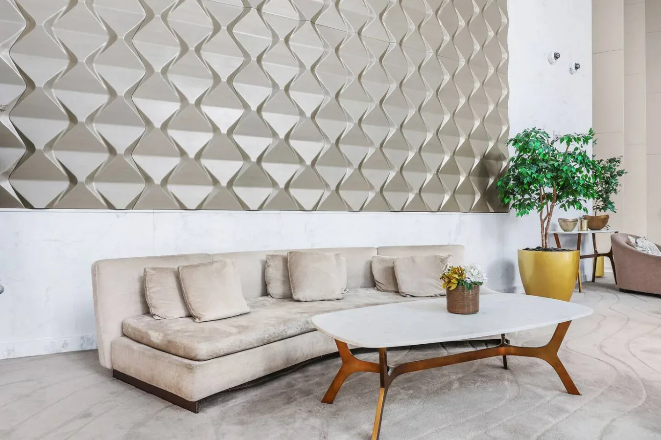 A bright lounge with a sectional seating area, coffee table, and potted plant.