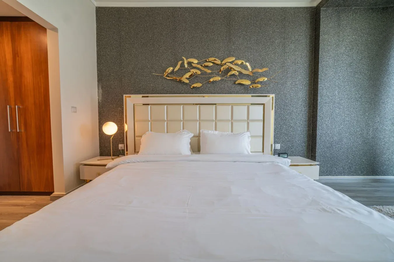 A bedroom with a neatly made bed and decorative wall art.