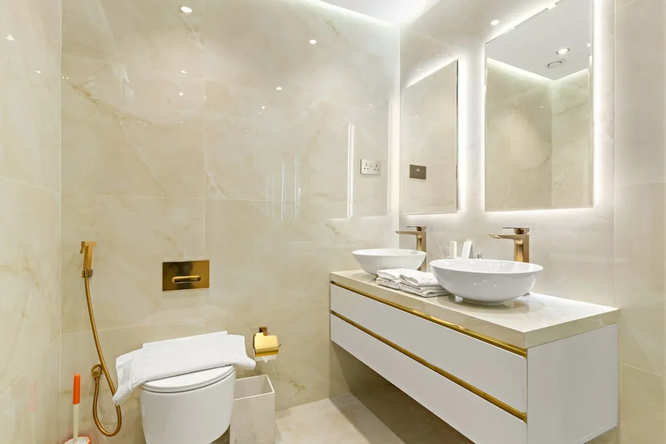 A bright bathroom with a toilet and a double-sink vanity.