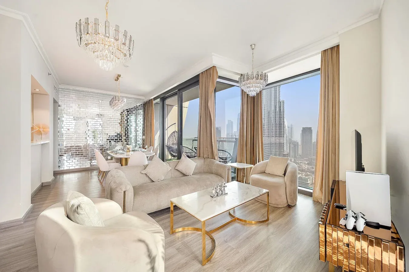 A bright living room with seating, a coffee table, and large city-facing windows.