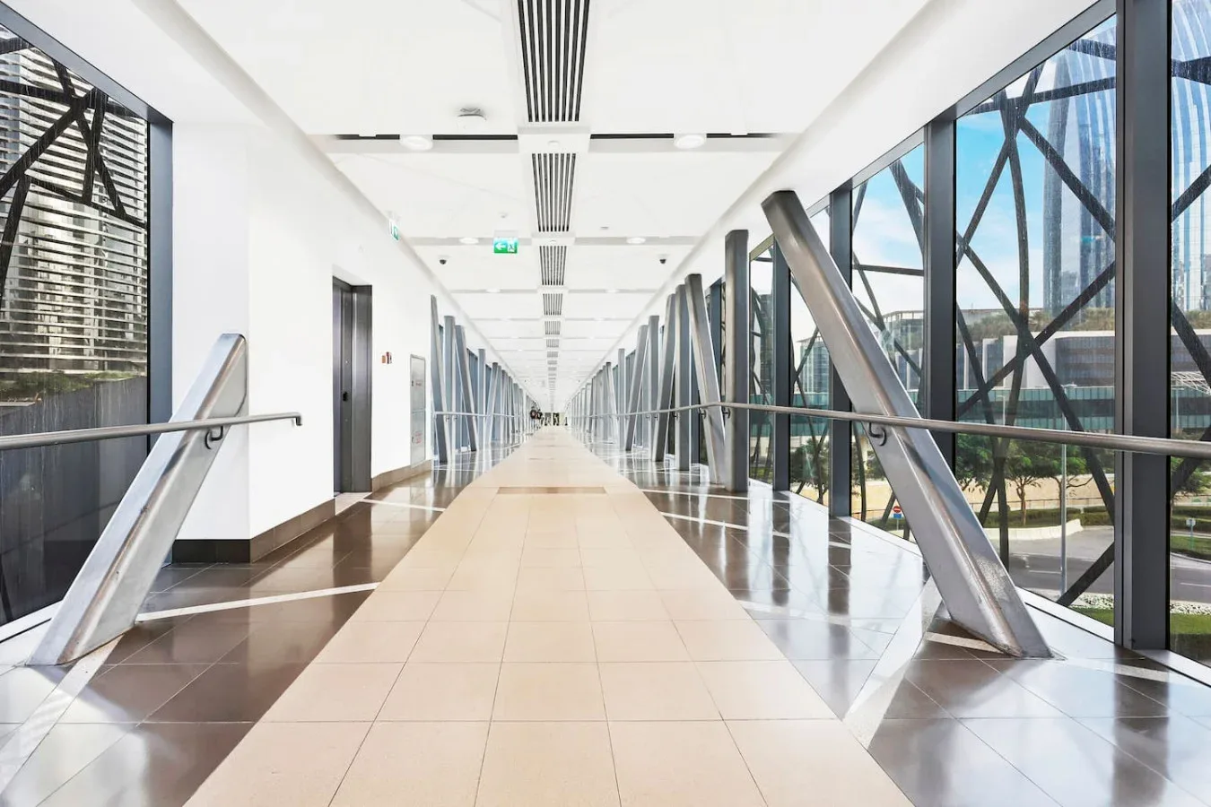 A long, bright corridor with large windows and metal structural supports.