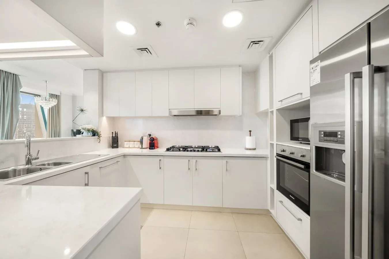 A bright white kitchen with a central cooktop and built-in appliances.