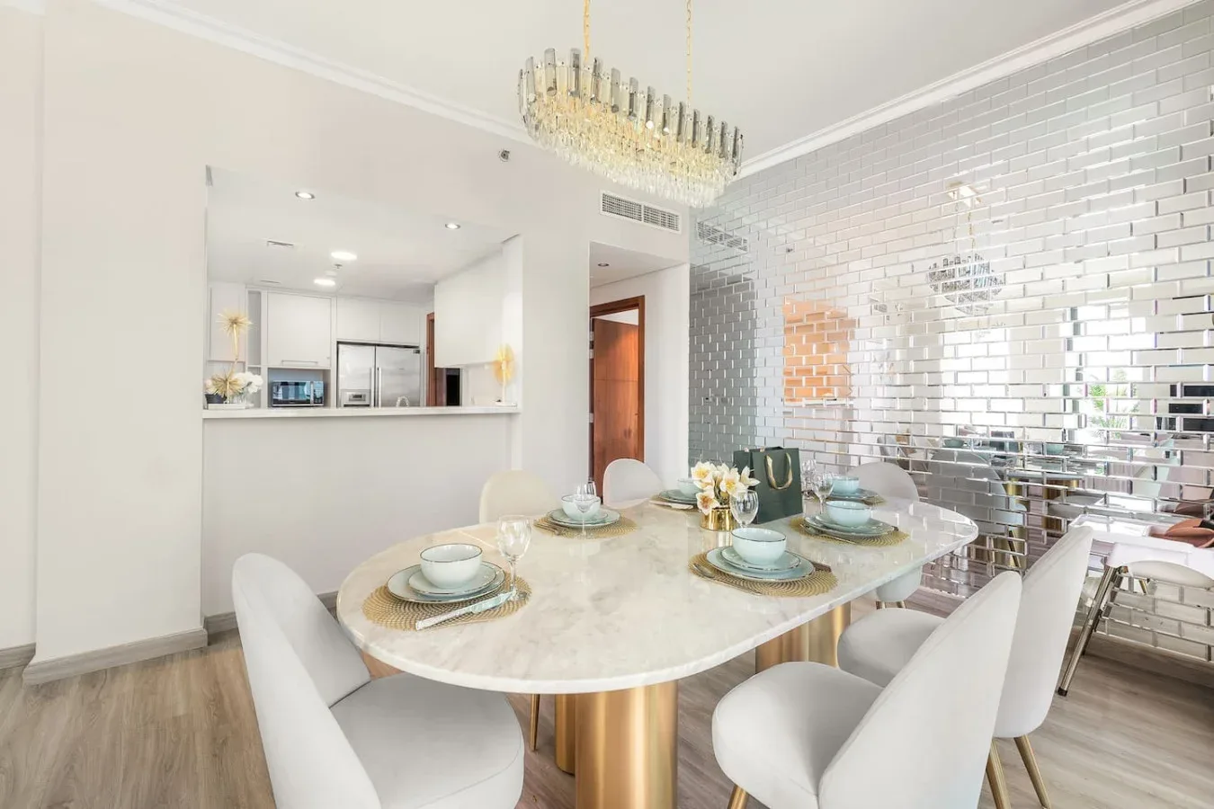 A dining area with a large oval table and upholstered seating beside a tiled wall.