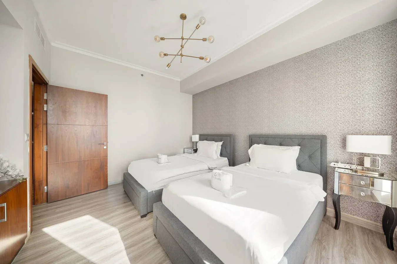 A bright bedroom with two beds and a bedside table.