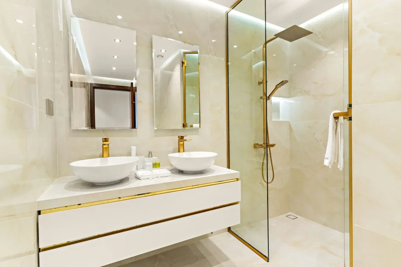A bright bathroom with a double-sink vanity and a glass-enclosed shower.