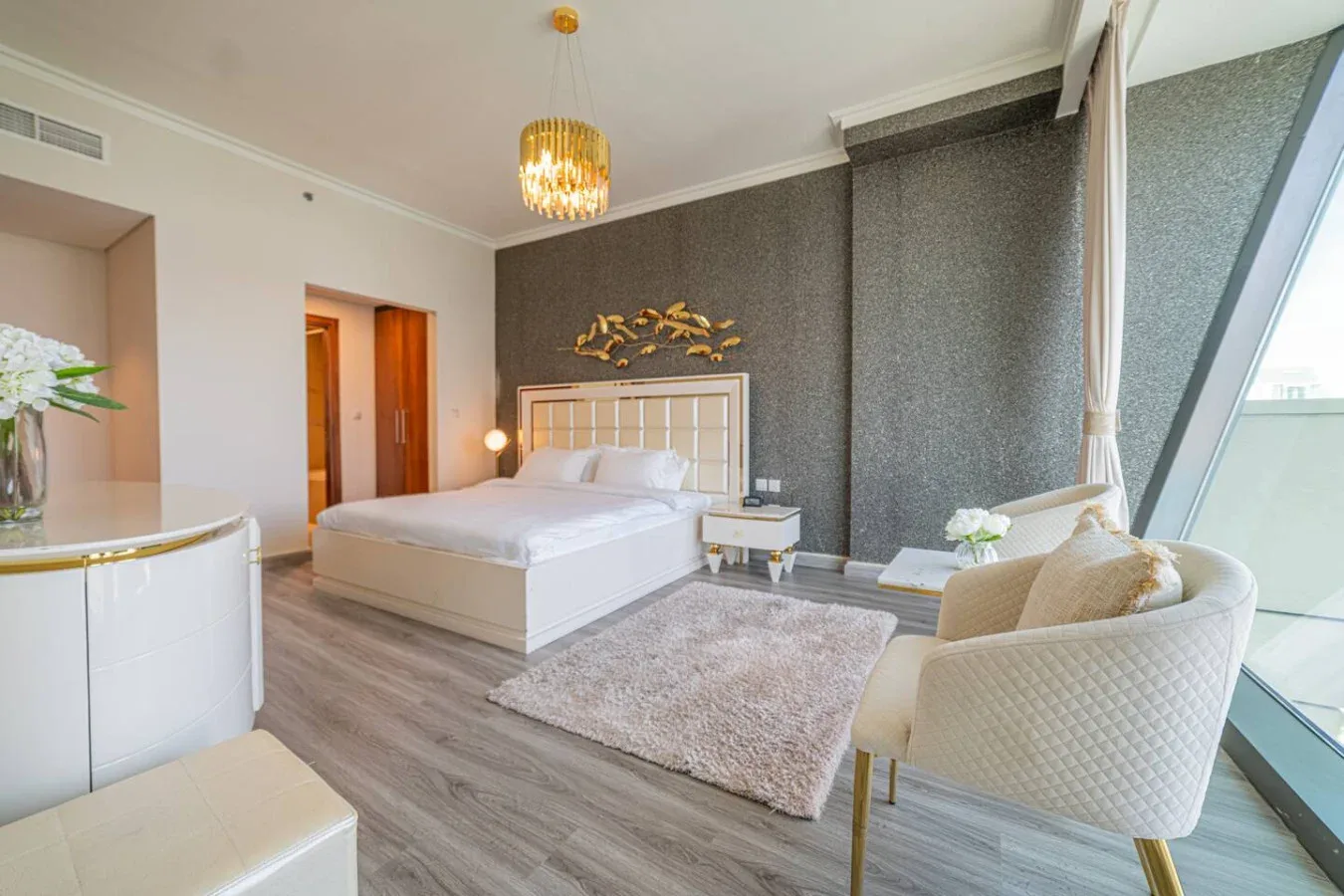 A bedroom with a bed, seating, and large windows.