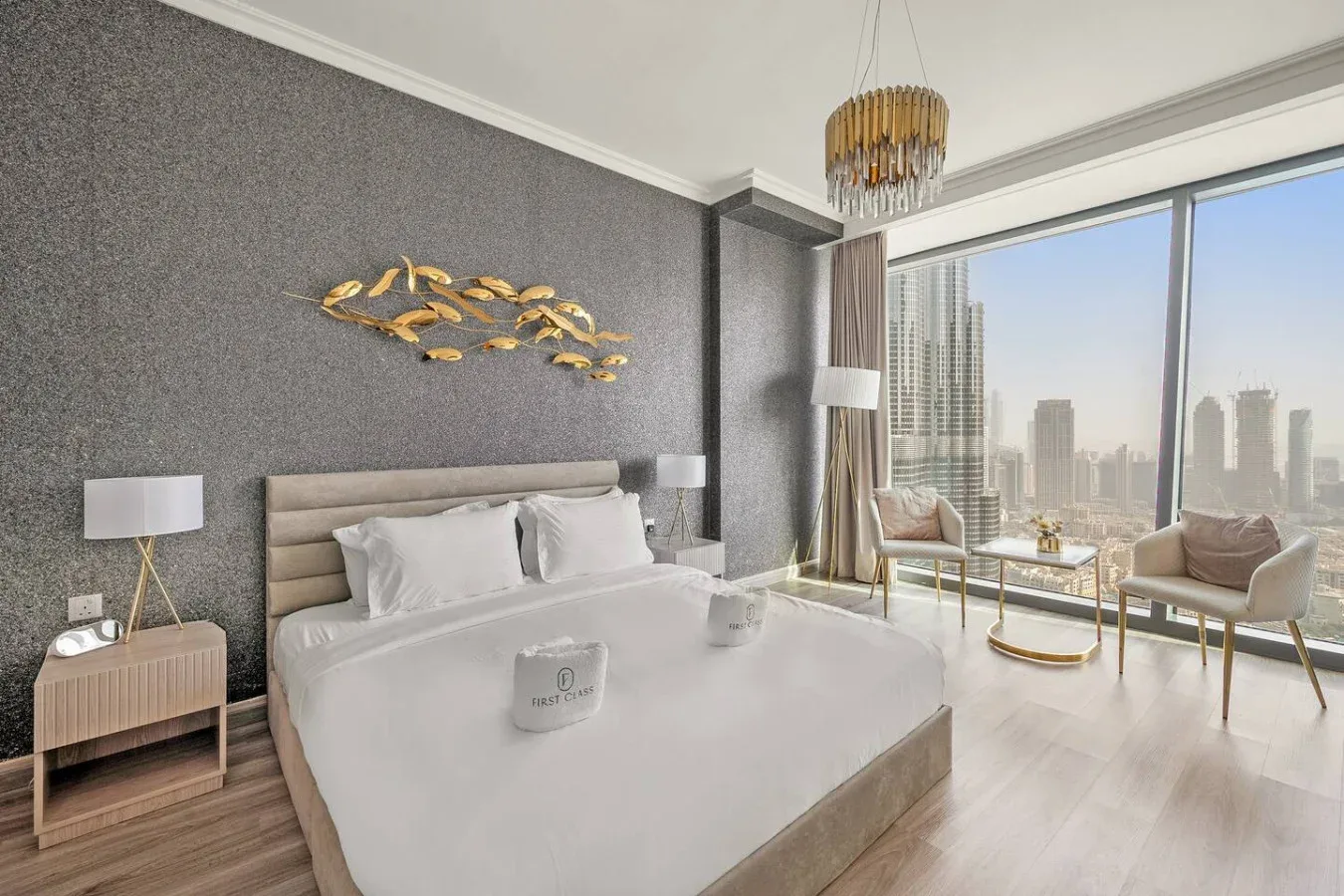 A bright bedroom with a large bed and floor-to-ceiling windows overlooking a city skyline.