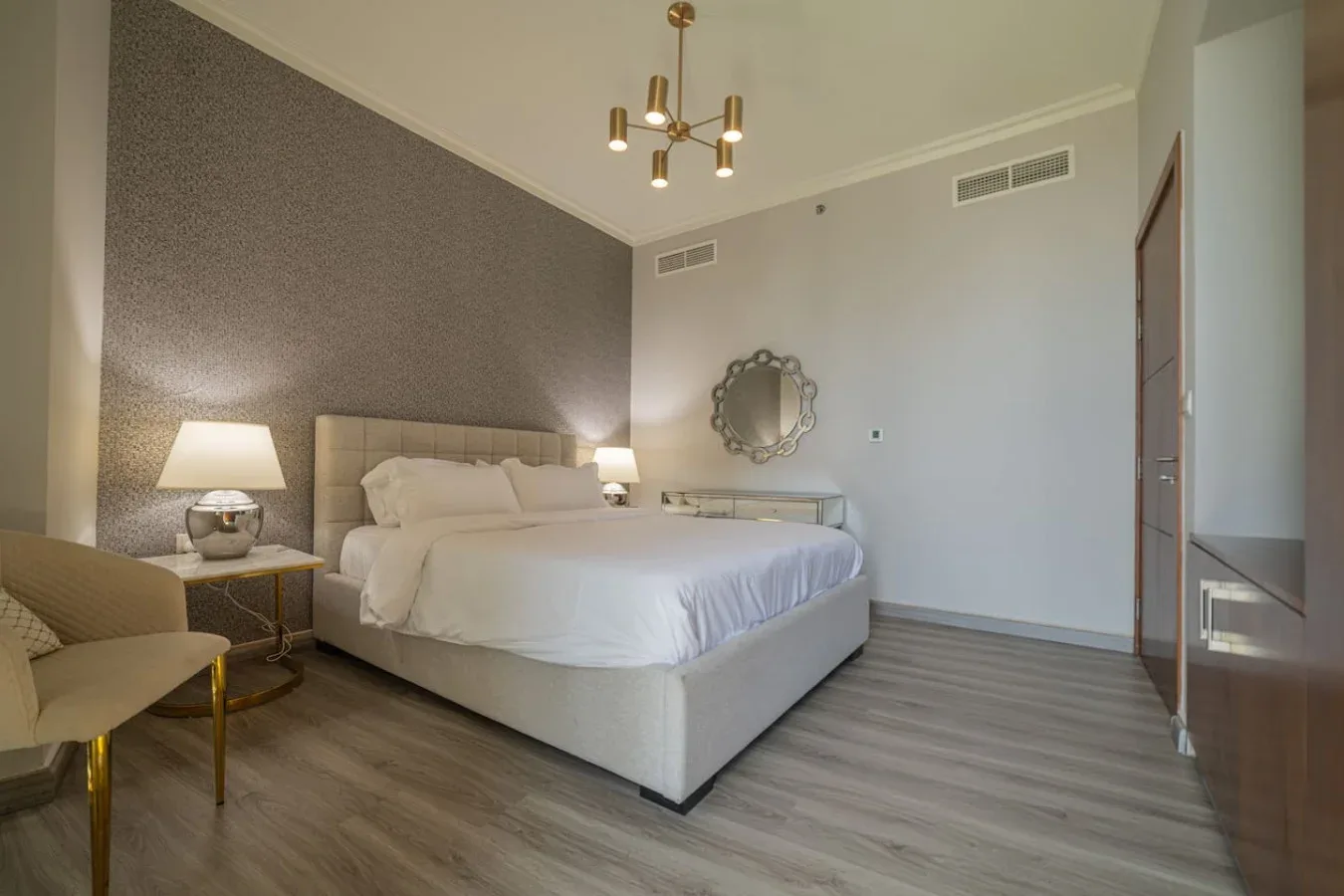 A bedroom with a large bed, bedside tables, and a decorative wall mirror.