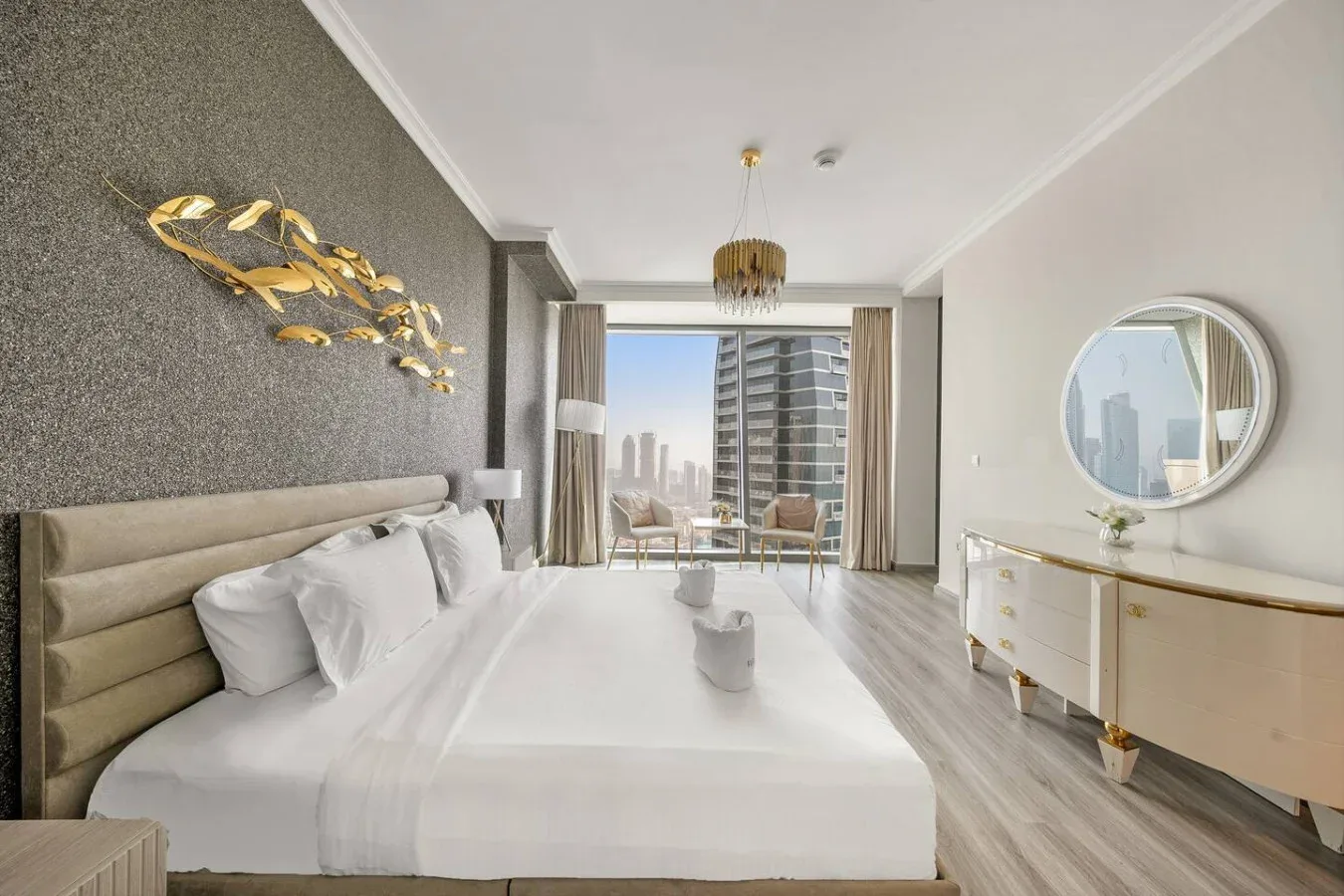 A bedroom with a large bed facing glass doors and a city view.
