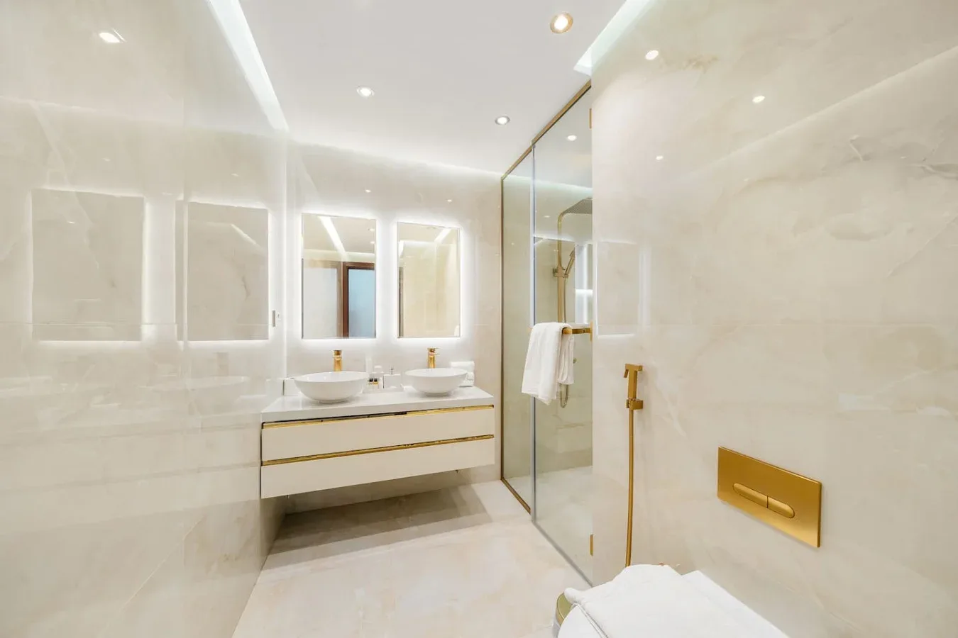 A bright bathroom with a double sink vanity and glass shower.