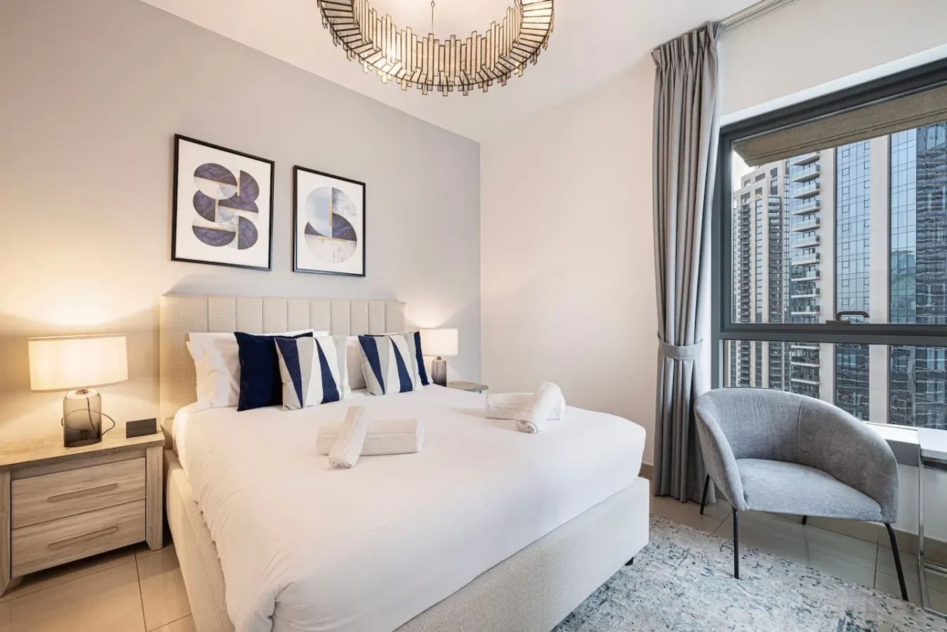 A bright bedroom with a neatly made bed and a large window.