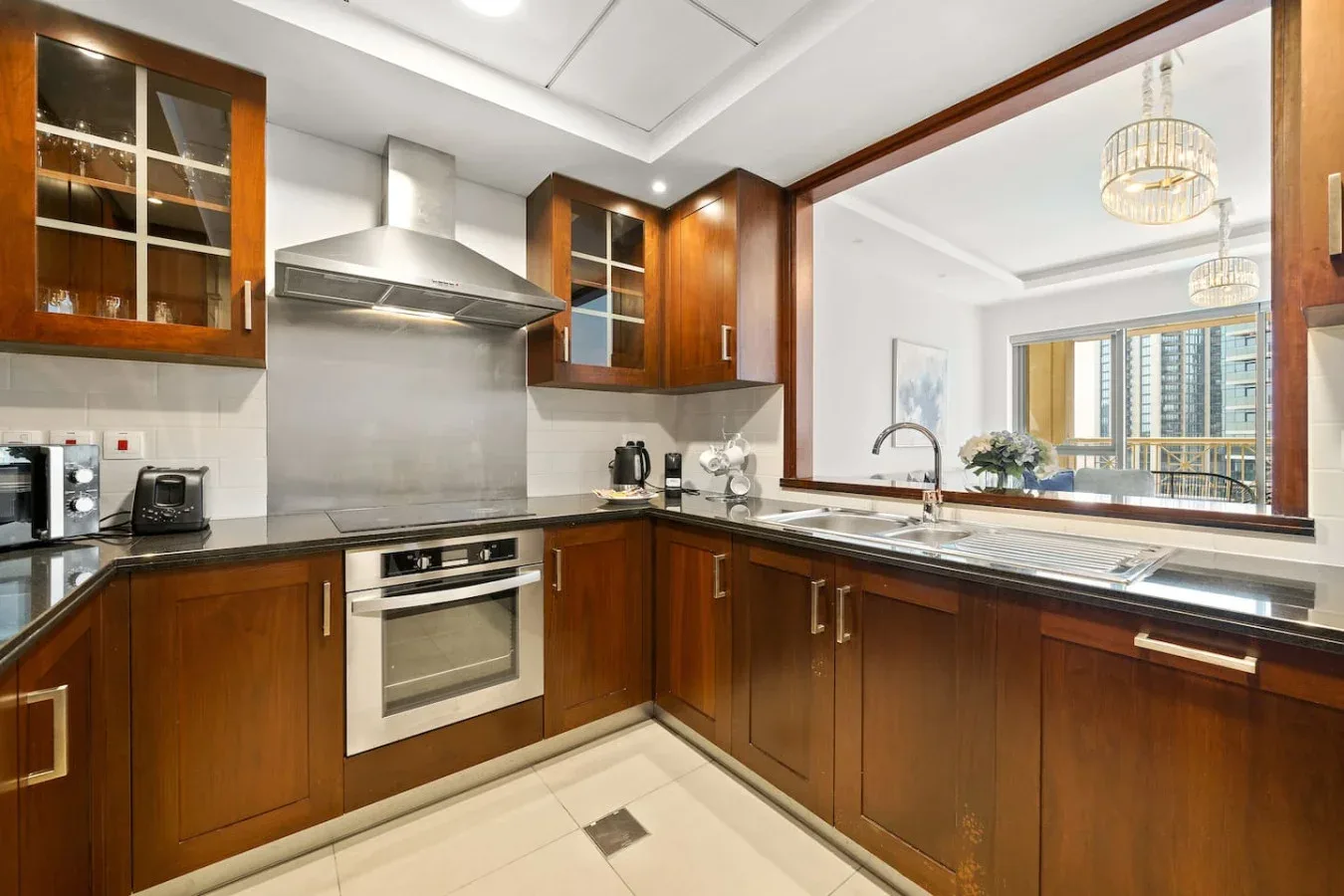 A modern kitchen with wooden cabinets, a countertop, and a large pass-through window.