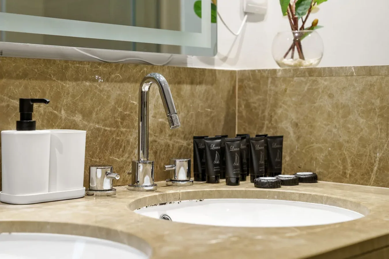 A bathroom vanity with a curved faucet, basin, and toiletries on the counter.
