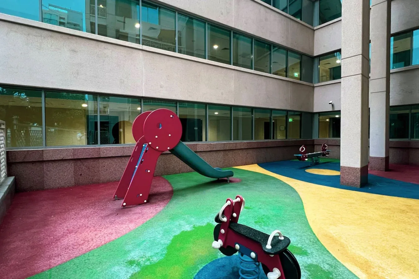 A colorful indoor play area has a slide and play equipment on a painted floor.
