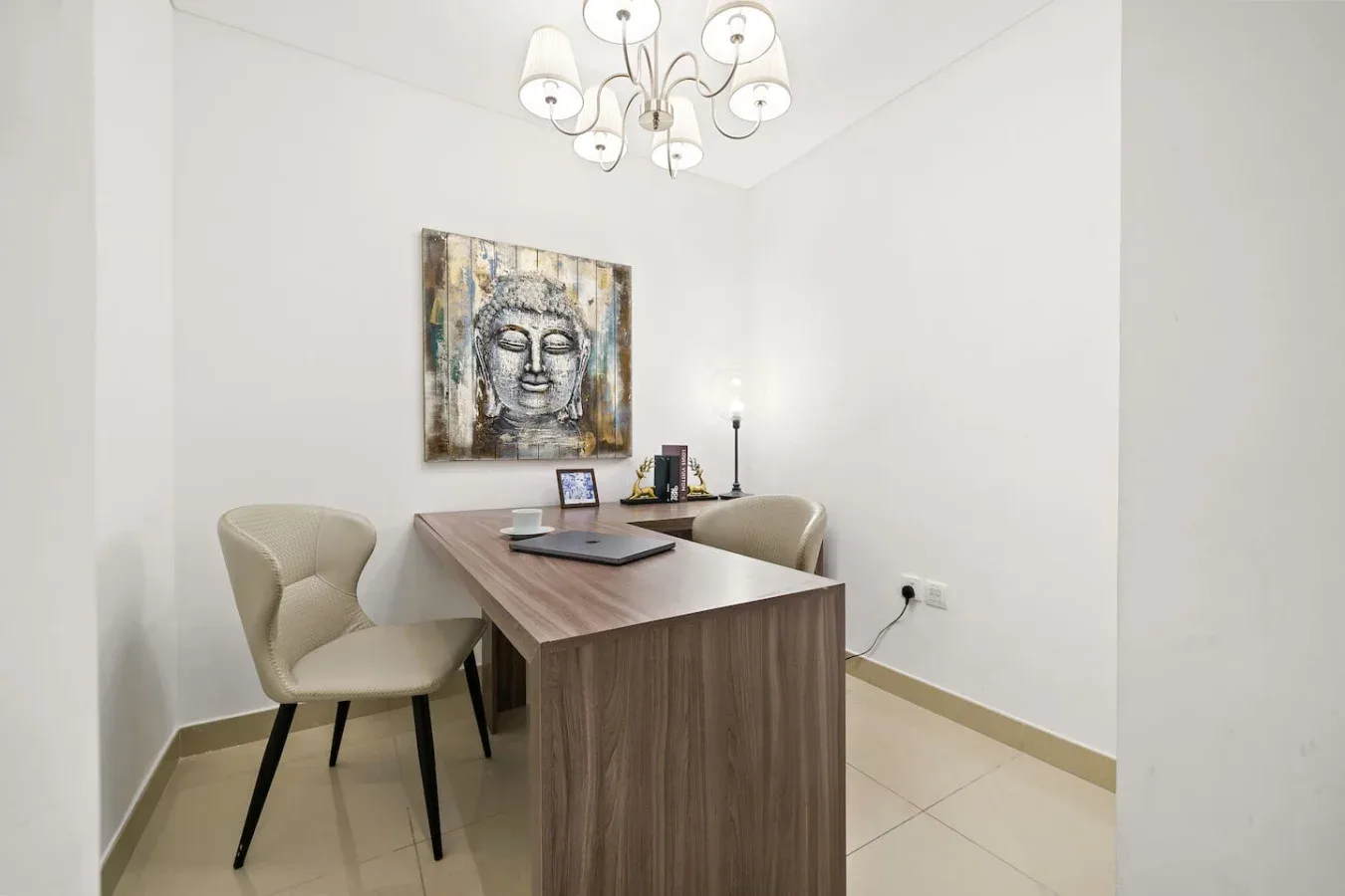 A small office with a desk, two chairs, and a Buddha painting.