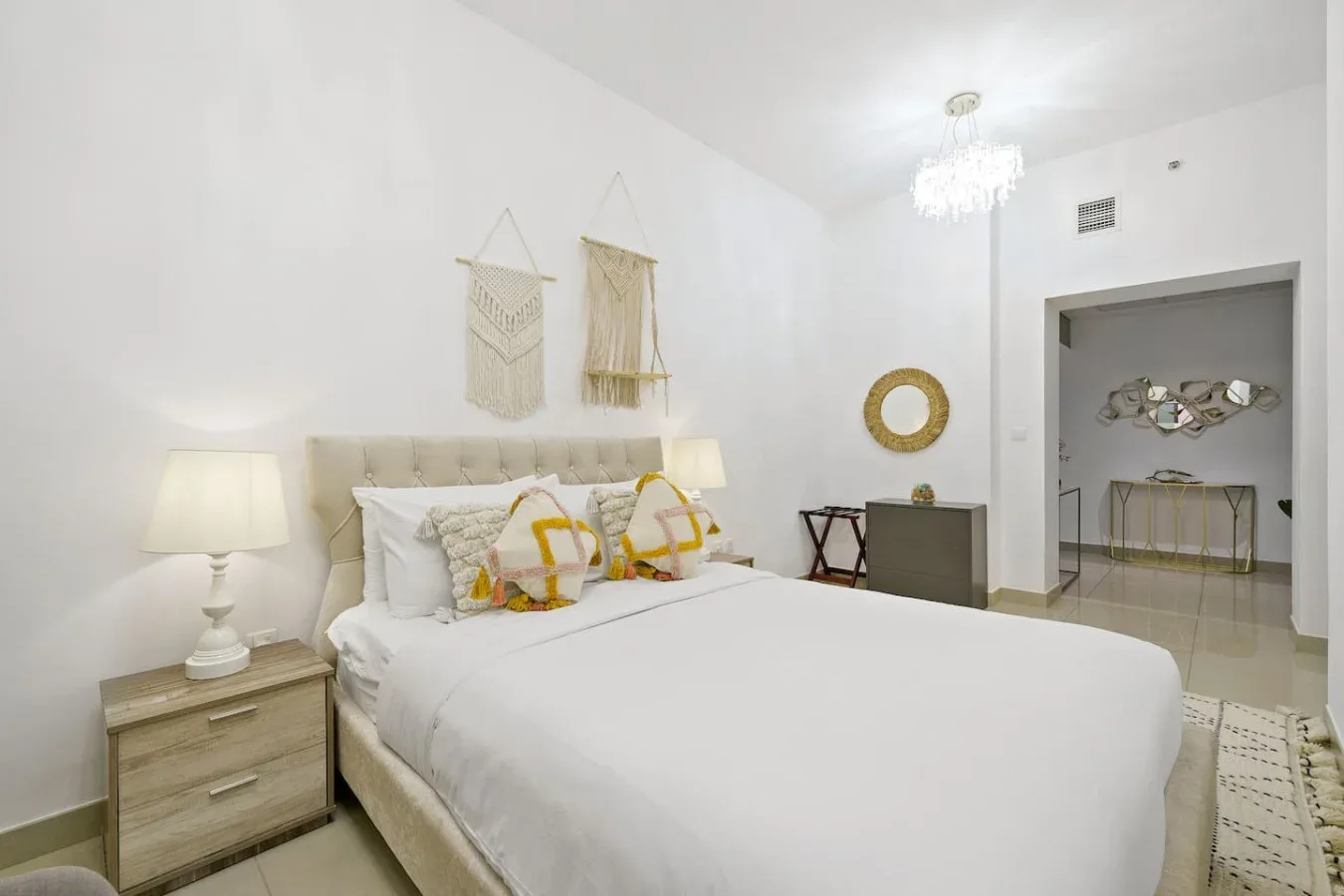 A bright bedroom with a neatly made bed and woven wall hangings.