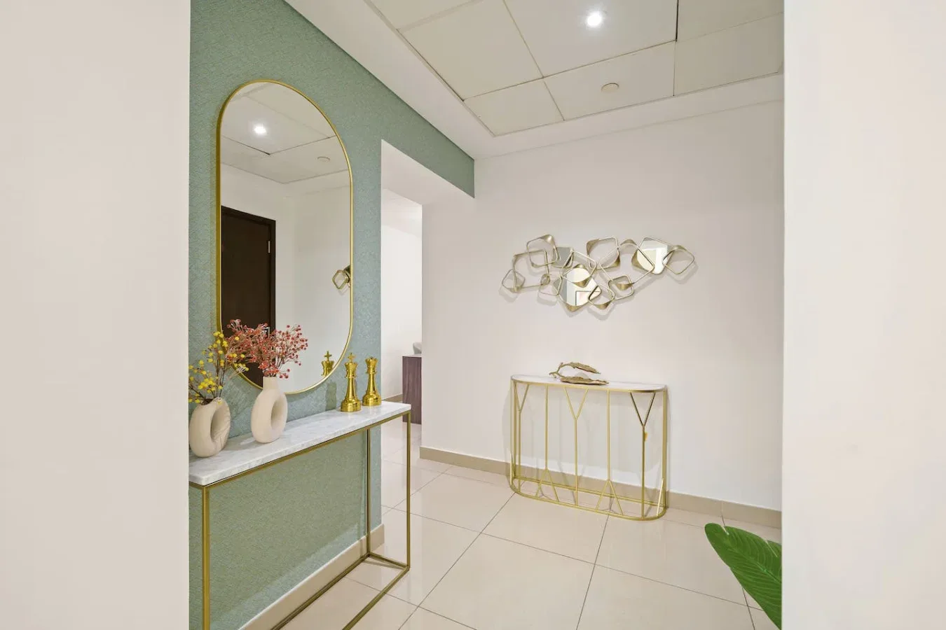 A bright interior hallway with a console table, wall mirror, and decorative wall sculpture.