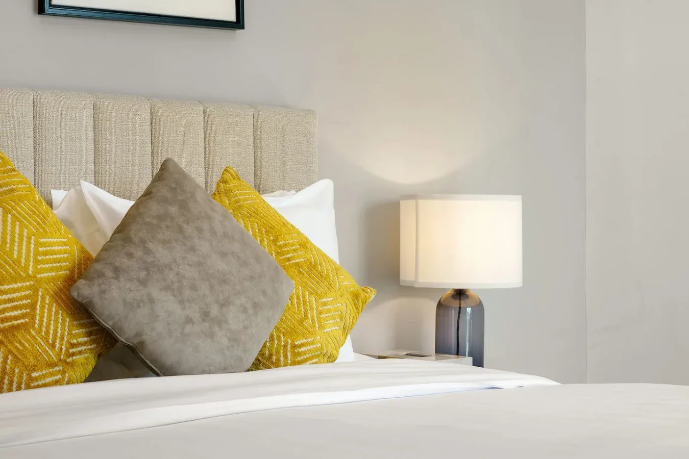 A bedroom with a neatly made bed and patterned accent pillows.