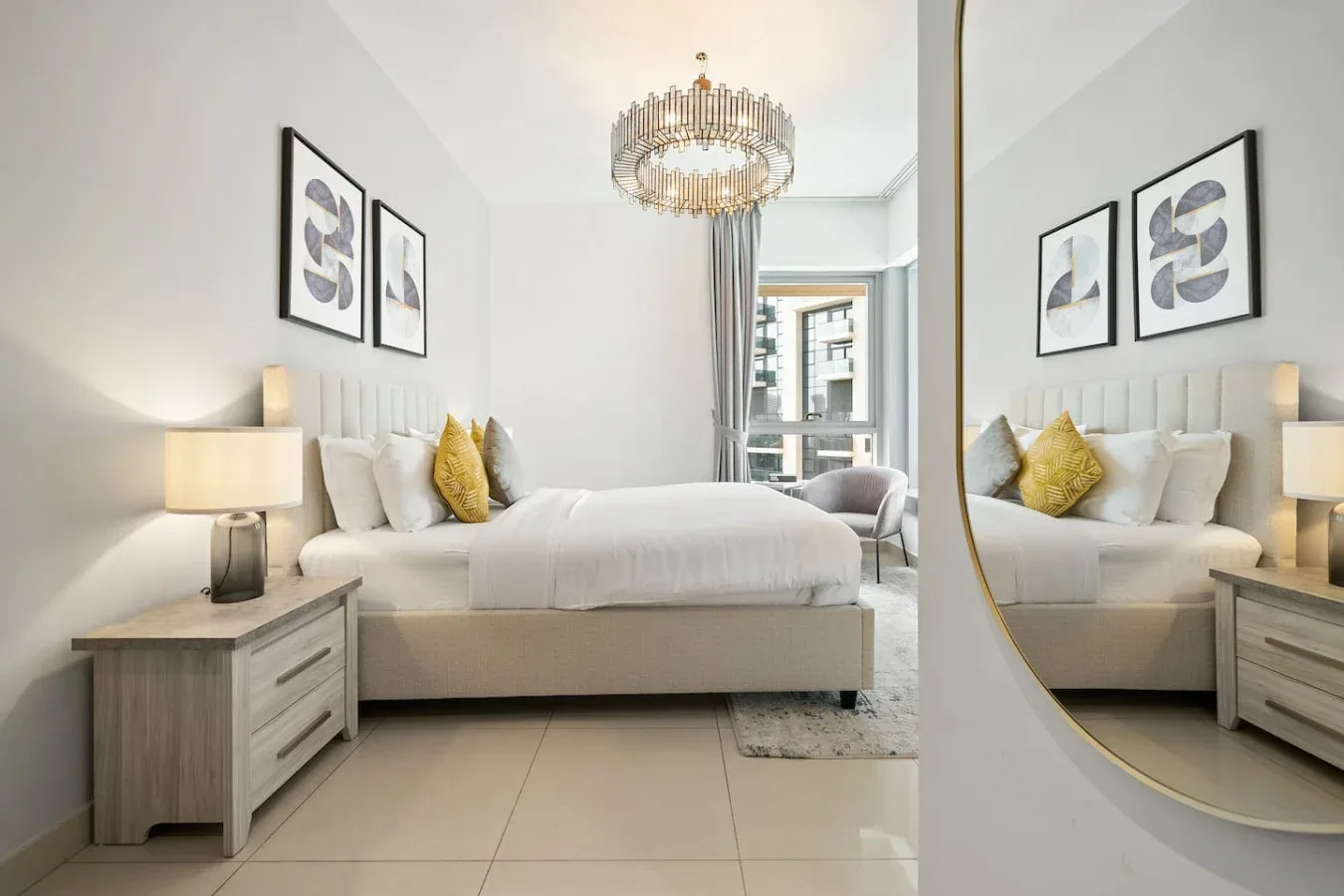 A bright bedroom with a bed, bedside tables, and a large wall mirror.