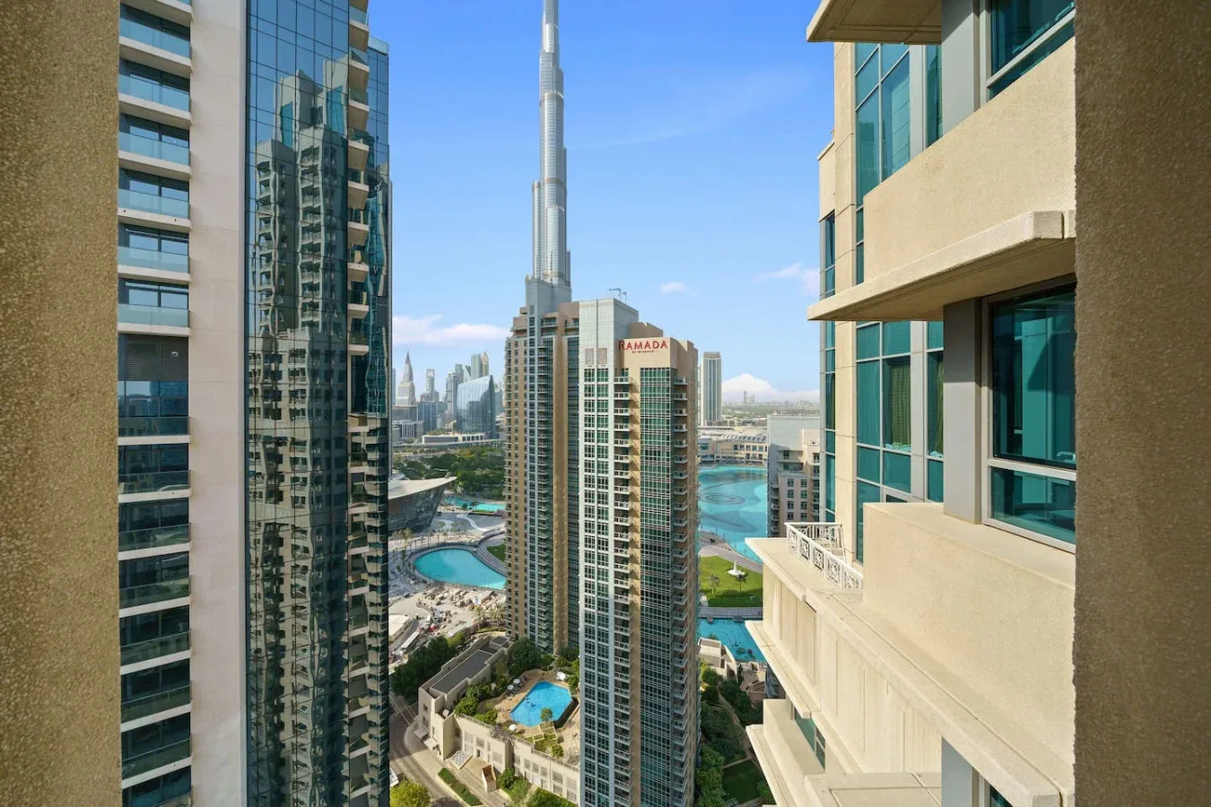 High-rise cityscape with glass towers, landscaped grounds, and a swimming pool.