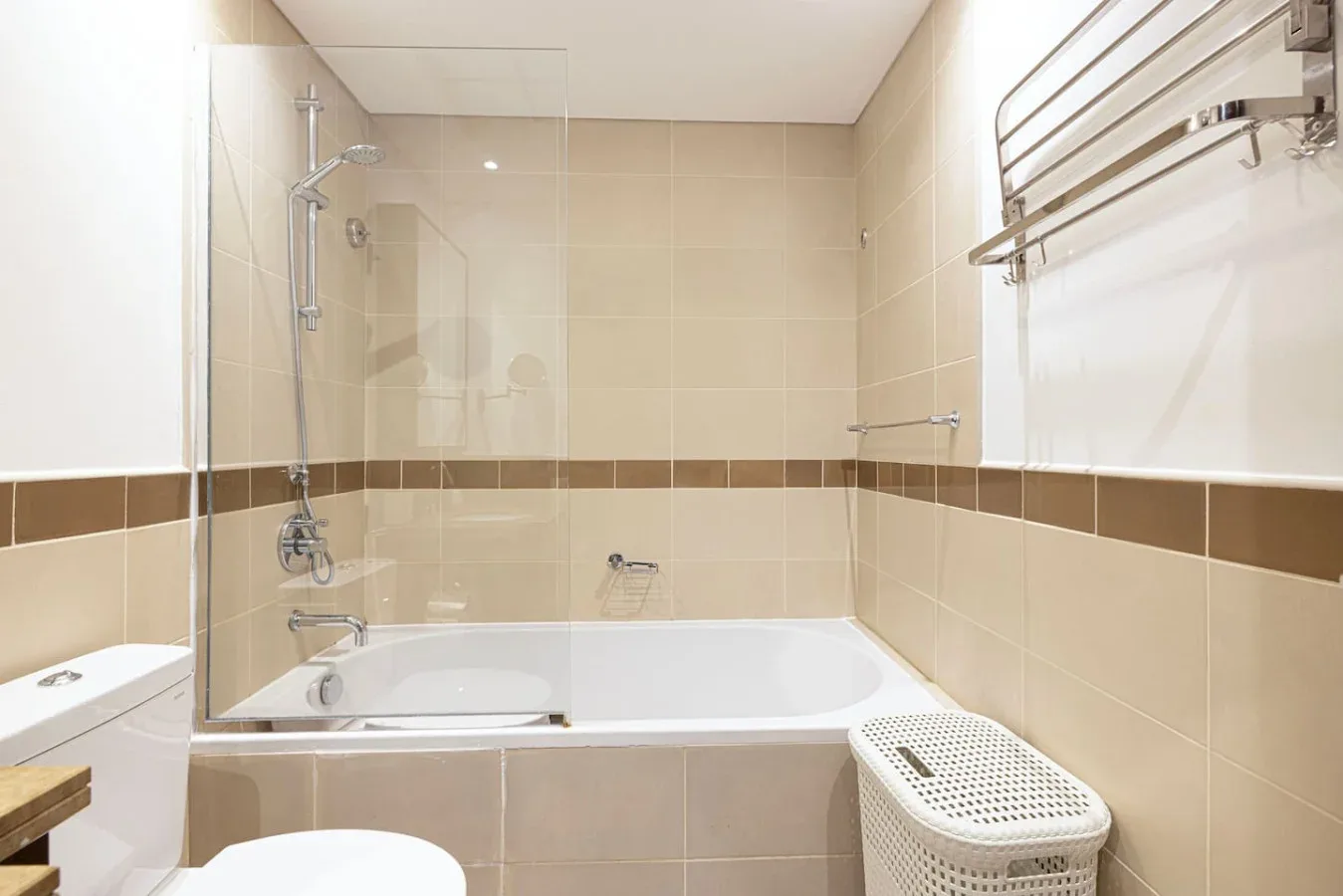 A tiled bathroom with a bathtub, shower, and laundry basket.