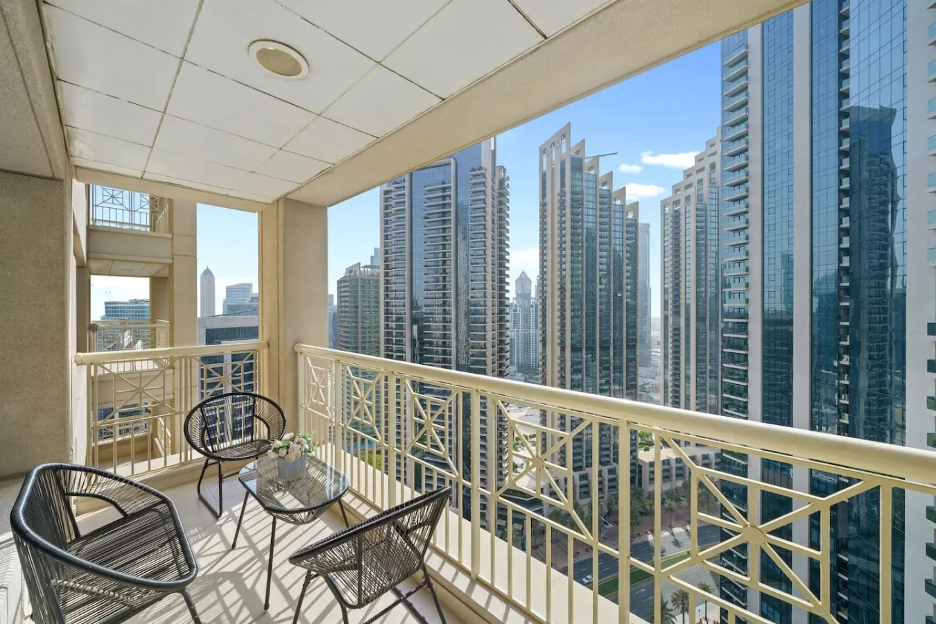 A balcony with outdoor seating overlooks a cluster of high-rise buildings.