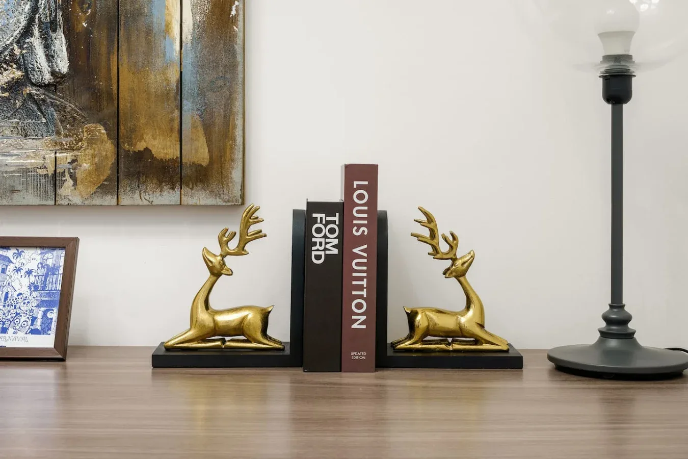 A tabletop display features gold-colored deer figures beside books and a lamp.