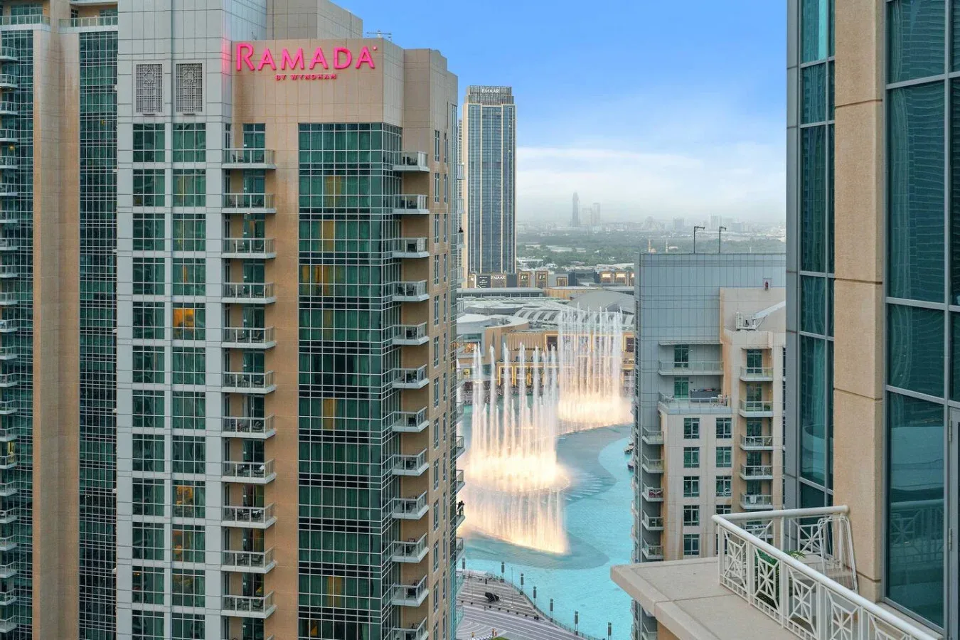 High-rise buildings overlook a pool with fountains in a modern city scene.