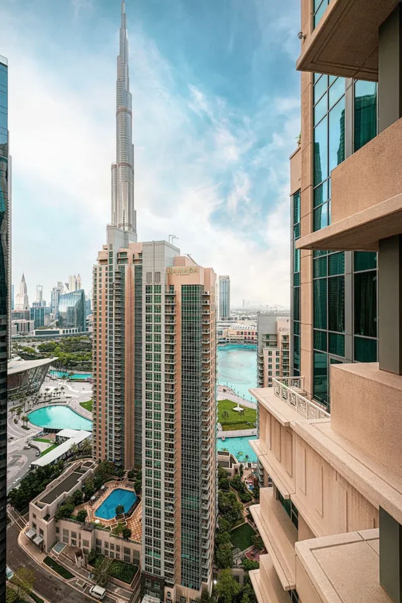 City skyline with a tall tower overlooking turquoise water and landscaped buildings.
