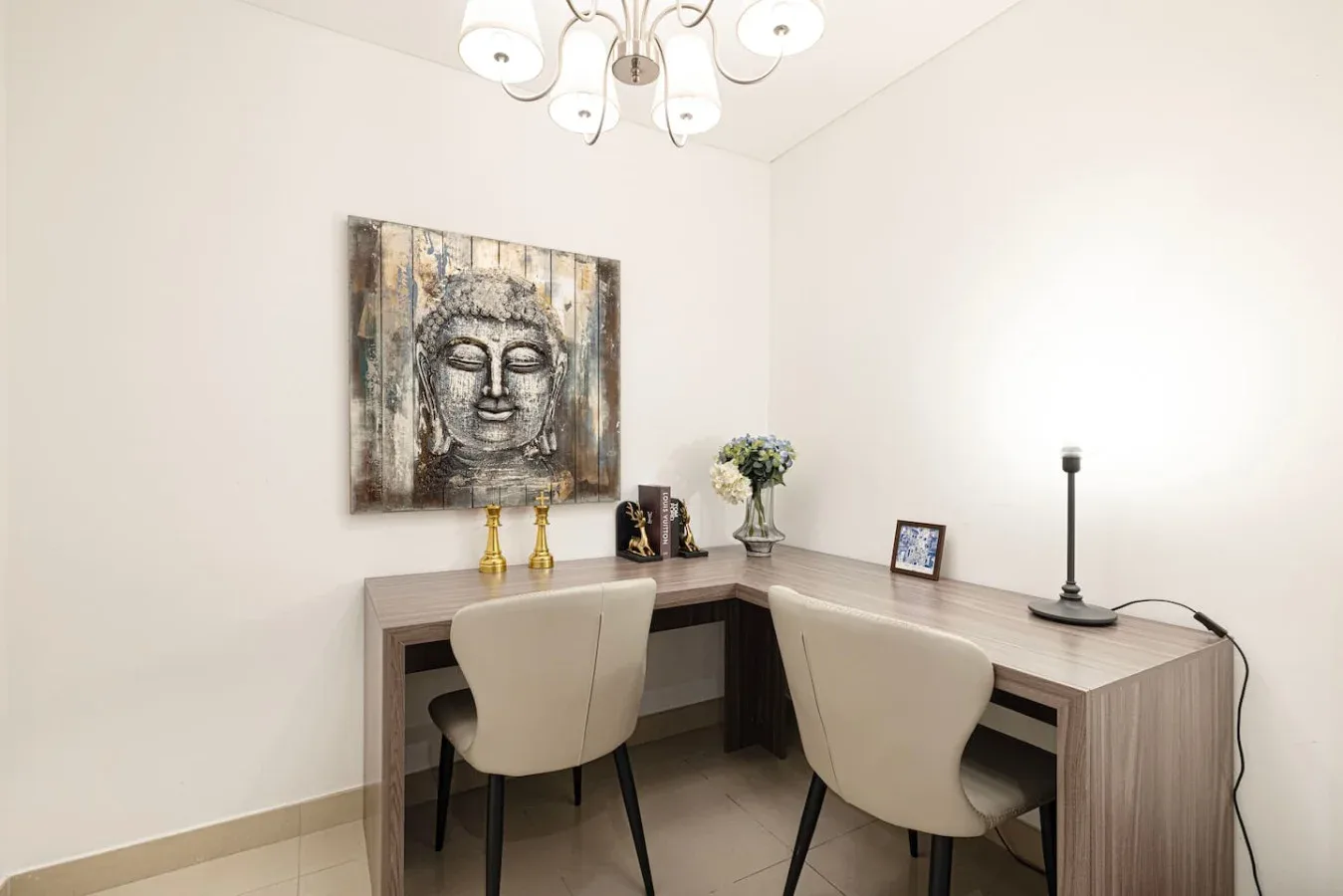 A corner desk with two chairs sits beneath a large Buddha painting.