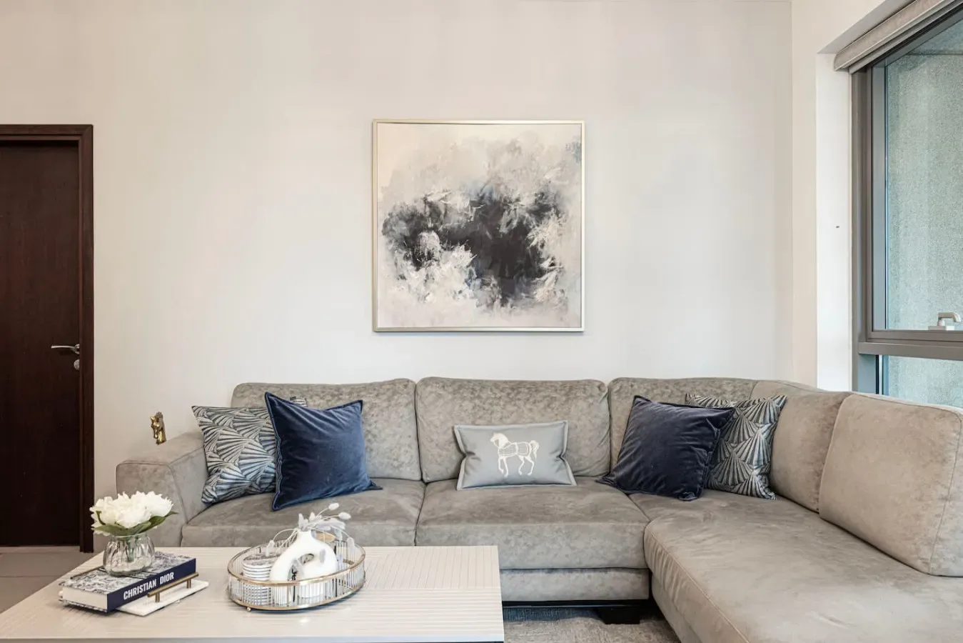 A living room with a sectional sofa and abstract artwork above it.