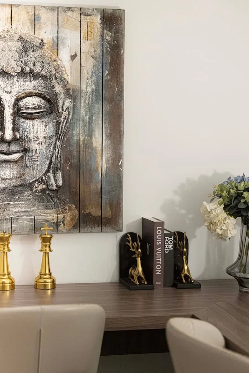 A dining area with a wooden table, gold candlesticks, and wall art.