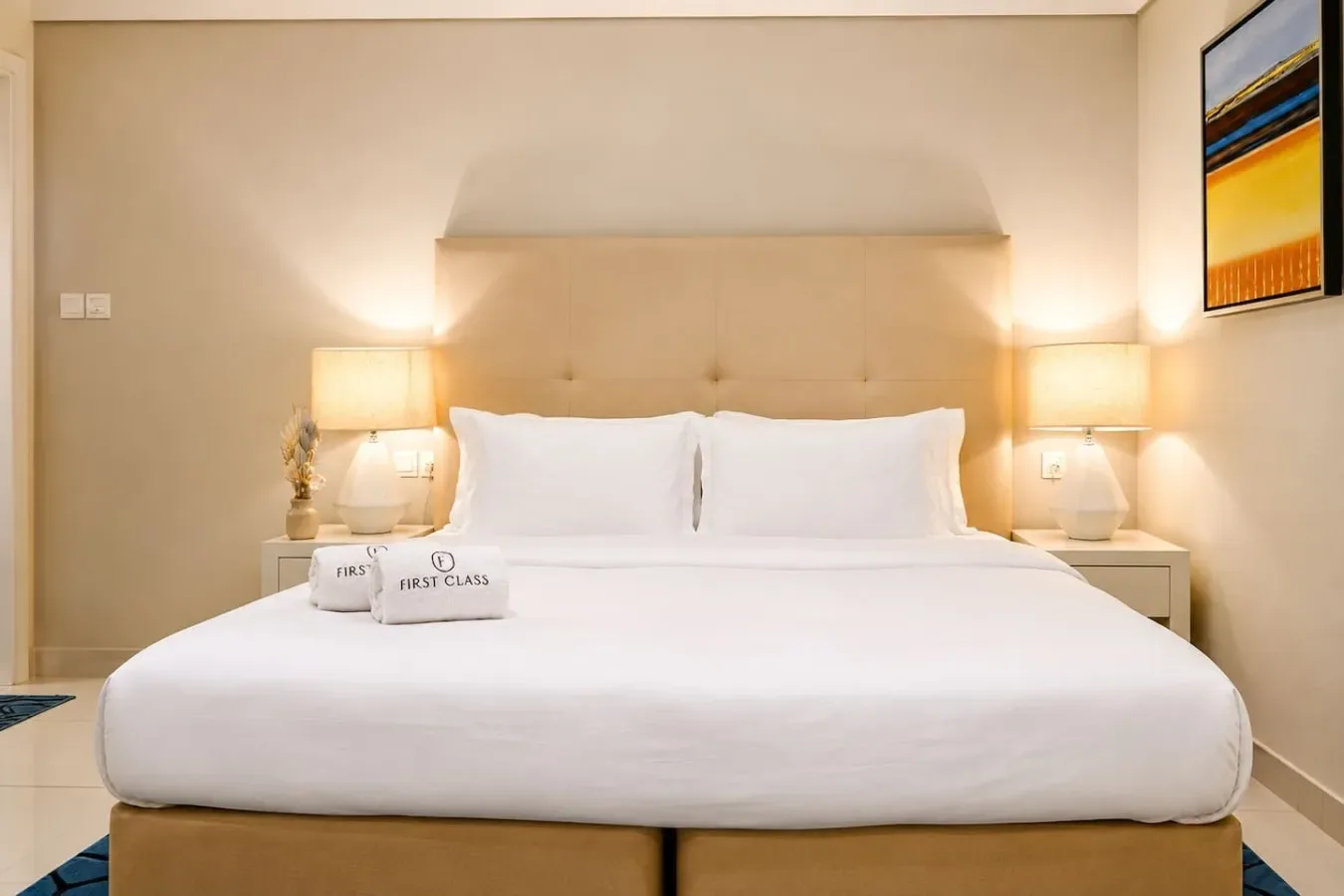 Una cama cuidadosamente tendida con ropa blanca está entre dos lámparas de noche.