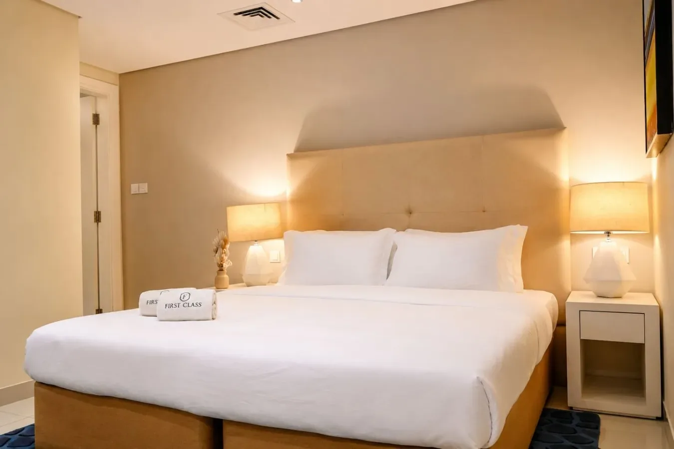 Un dormitorio con una cama grande, ropa de cama blanca y lámparas de noche.