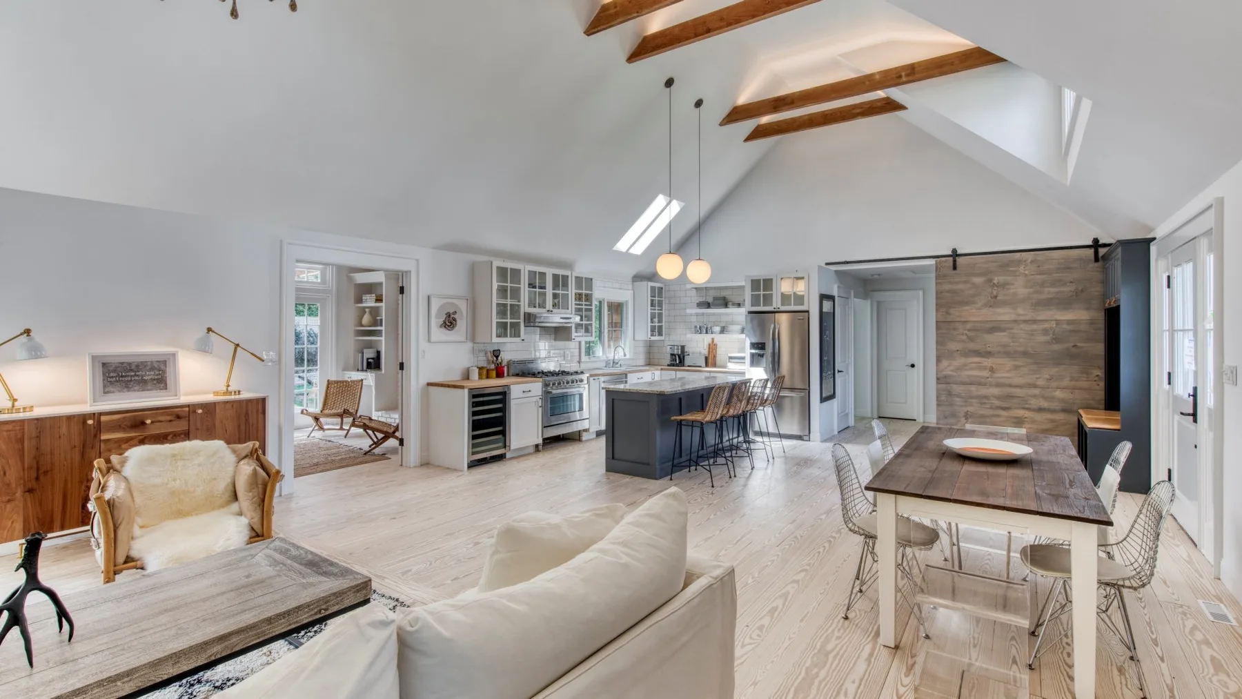 Una sala de estar y cocina de concepto abierto con una mesa de comedor y vigas vistas.