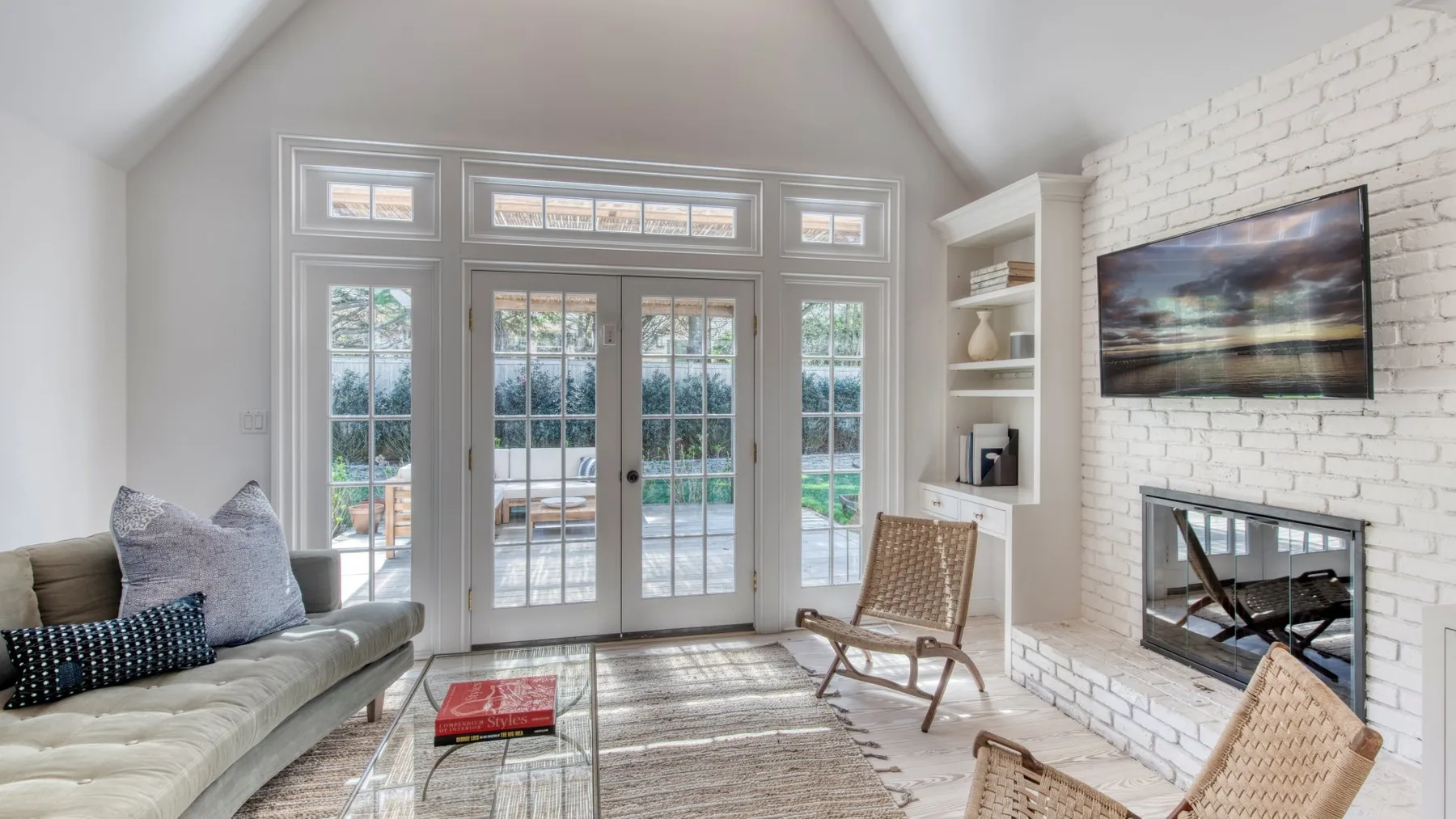 Una sala de estar luminosa tiene ventanas altas, asientos y una chimenea.