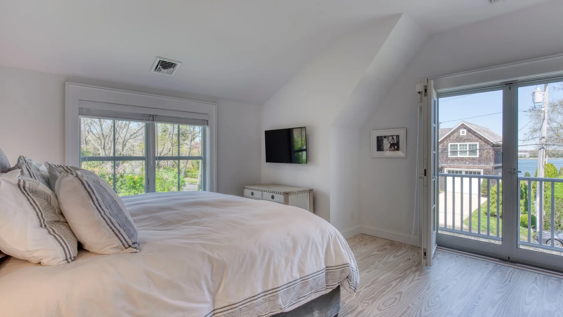 Dormitorio luminoso con una cama junto a una ventana y puertas de vidrio que dan a un balcón.