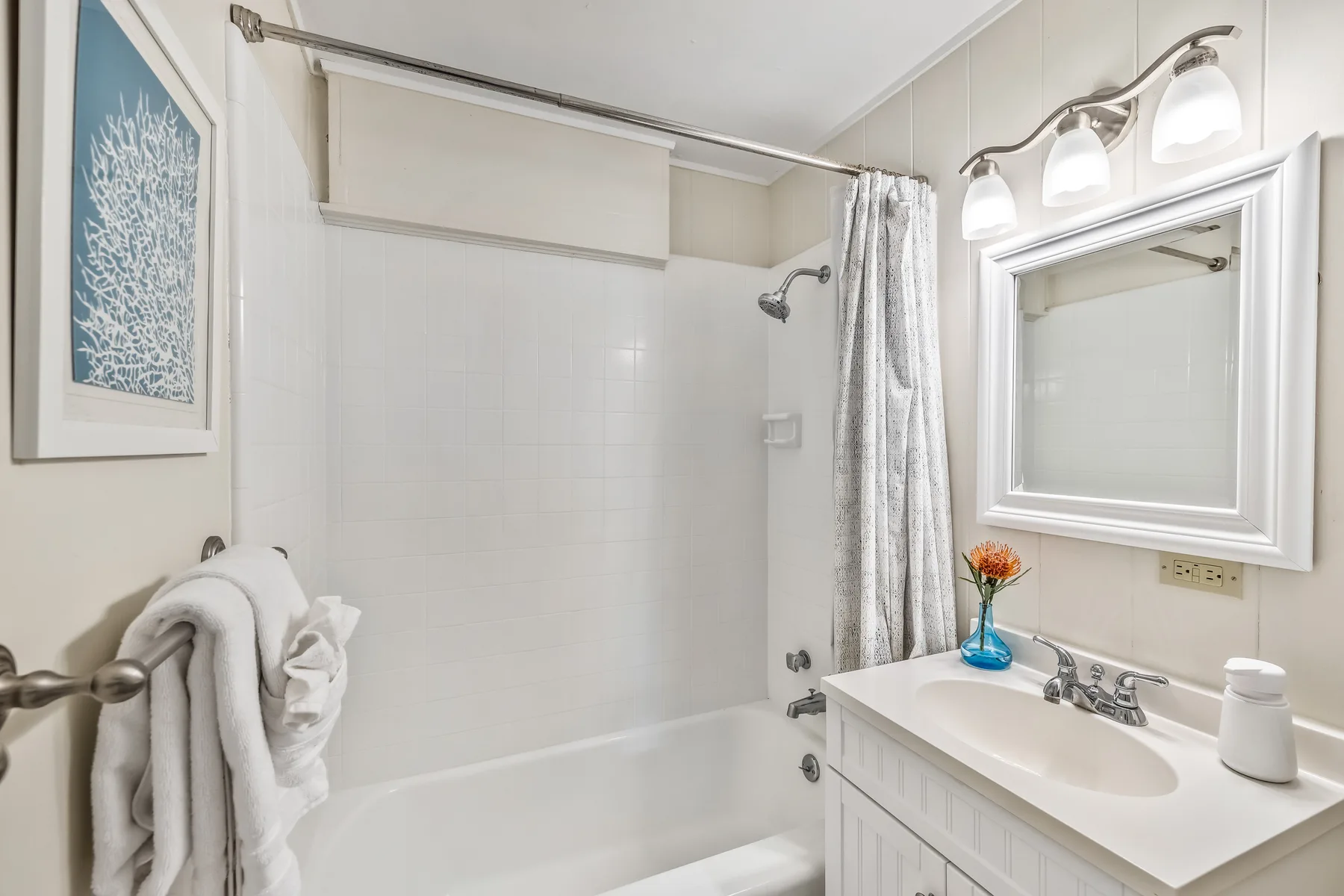 A bright bathroom with a bathtub, shower curtain, and vanity.