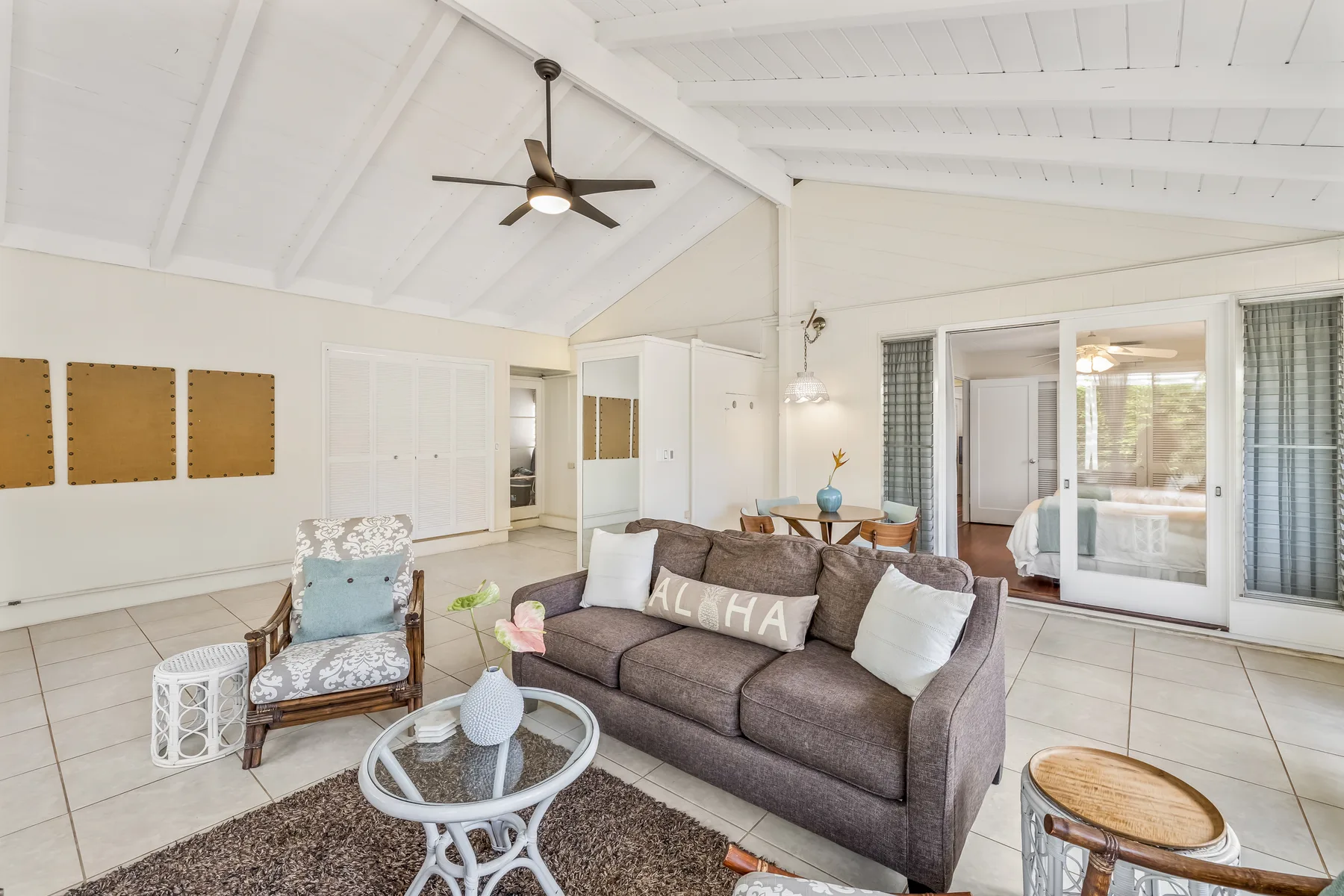 A bright living room with seating, a glass coffee table, and sliding glass doors.