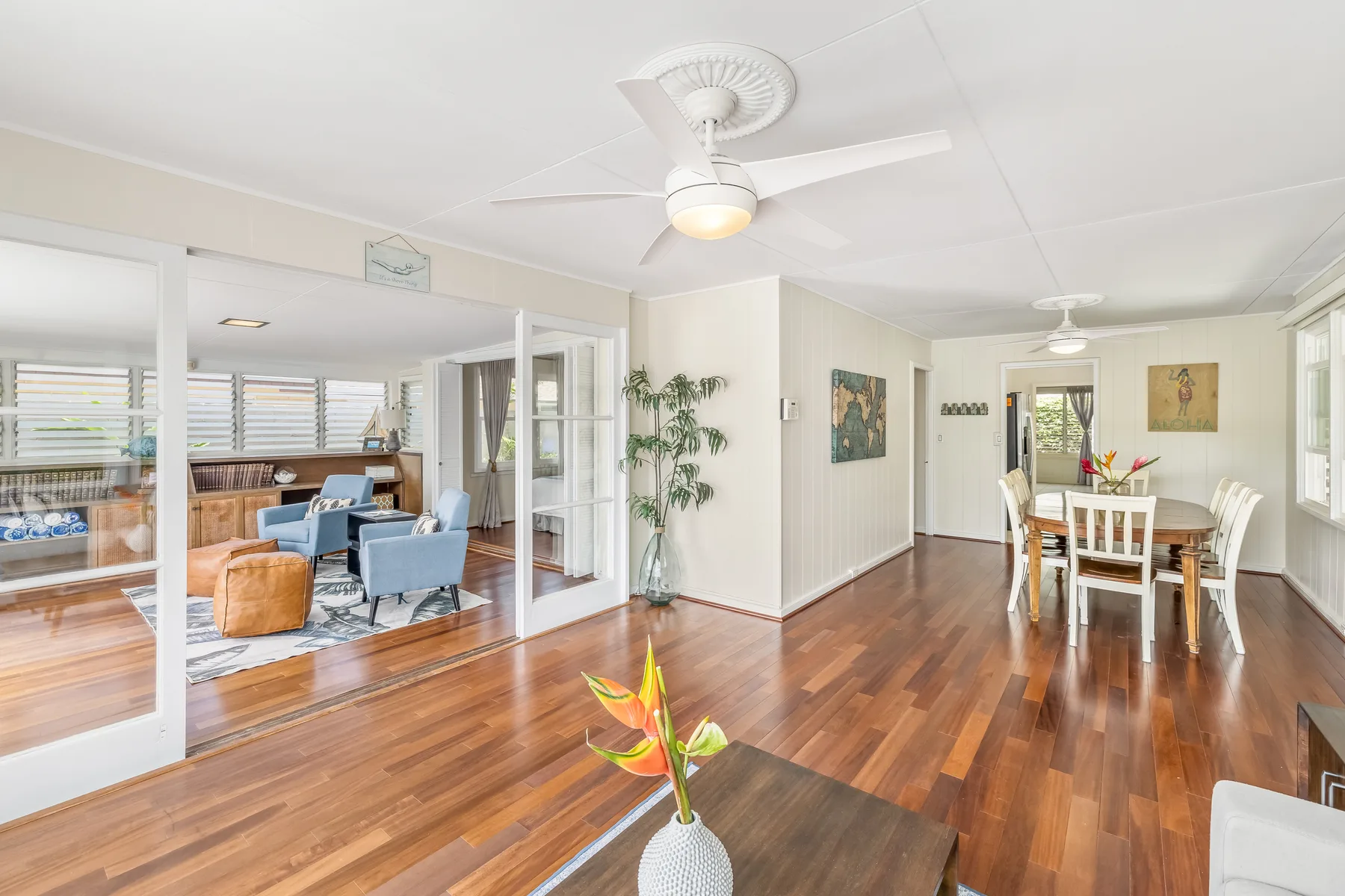A bright open-plan living and dining room with wood flooring and ceiling fans.