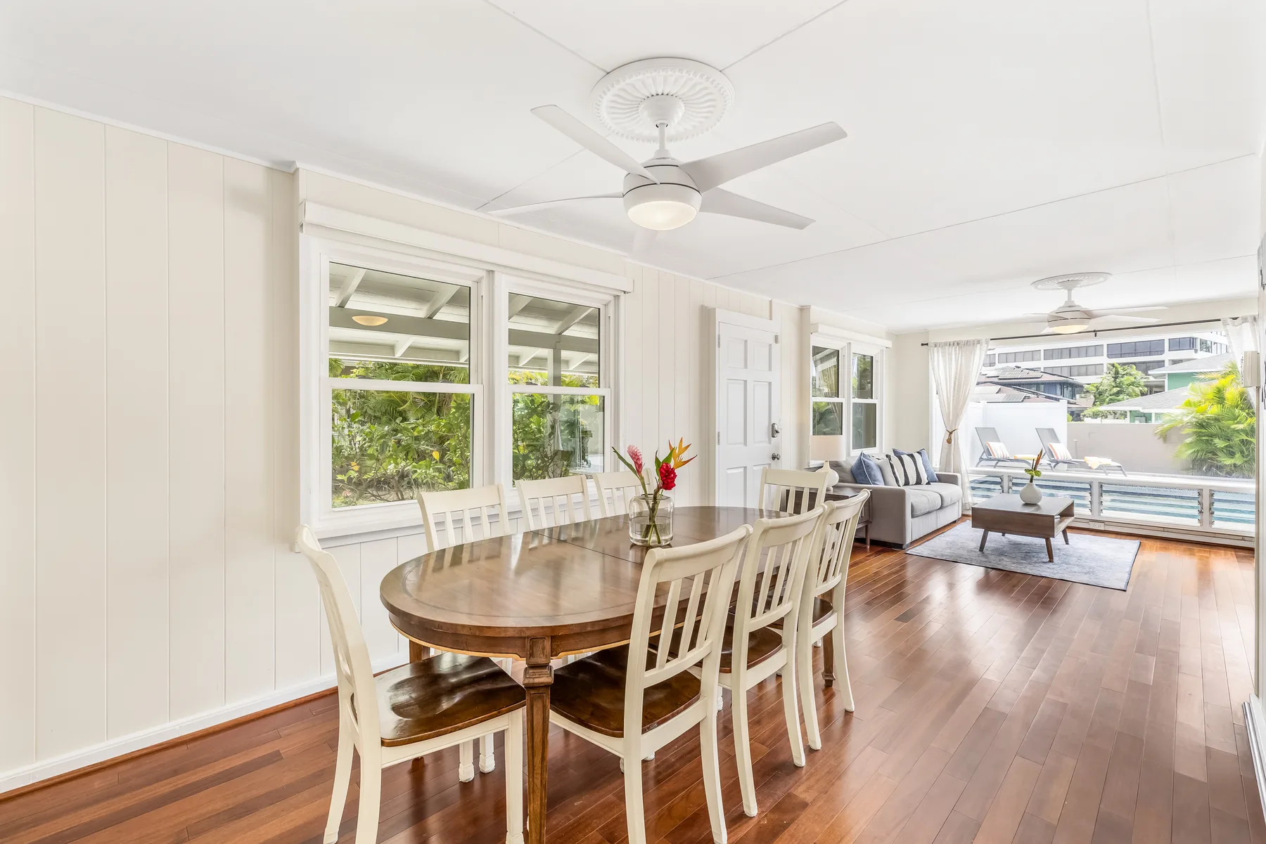 A bright open-plan dining and living room with a wooden table and seating.