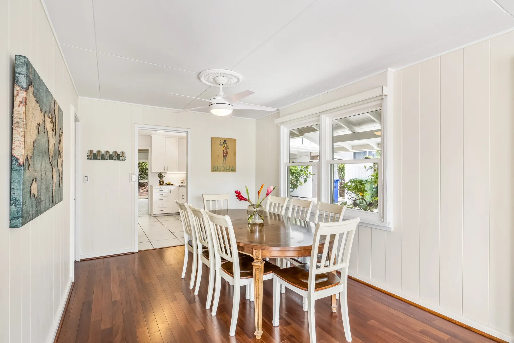 A bright dining room with a wooden table and white seating beside large windows.