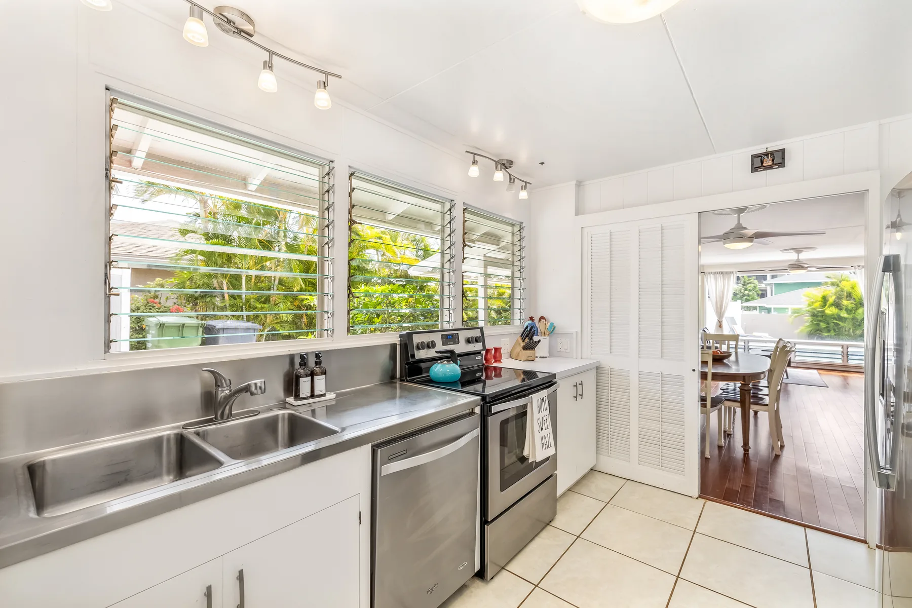 A bright kitchen with stainless steel counters and a view into a dining area.