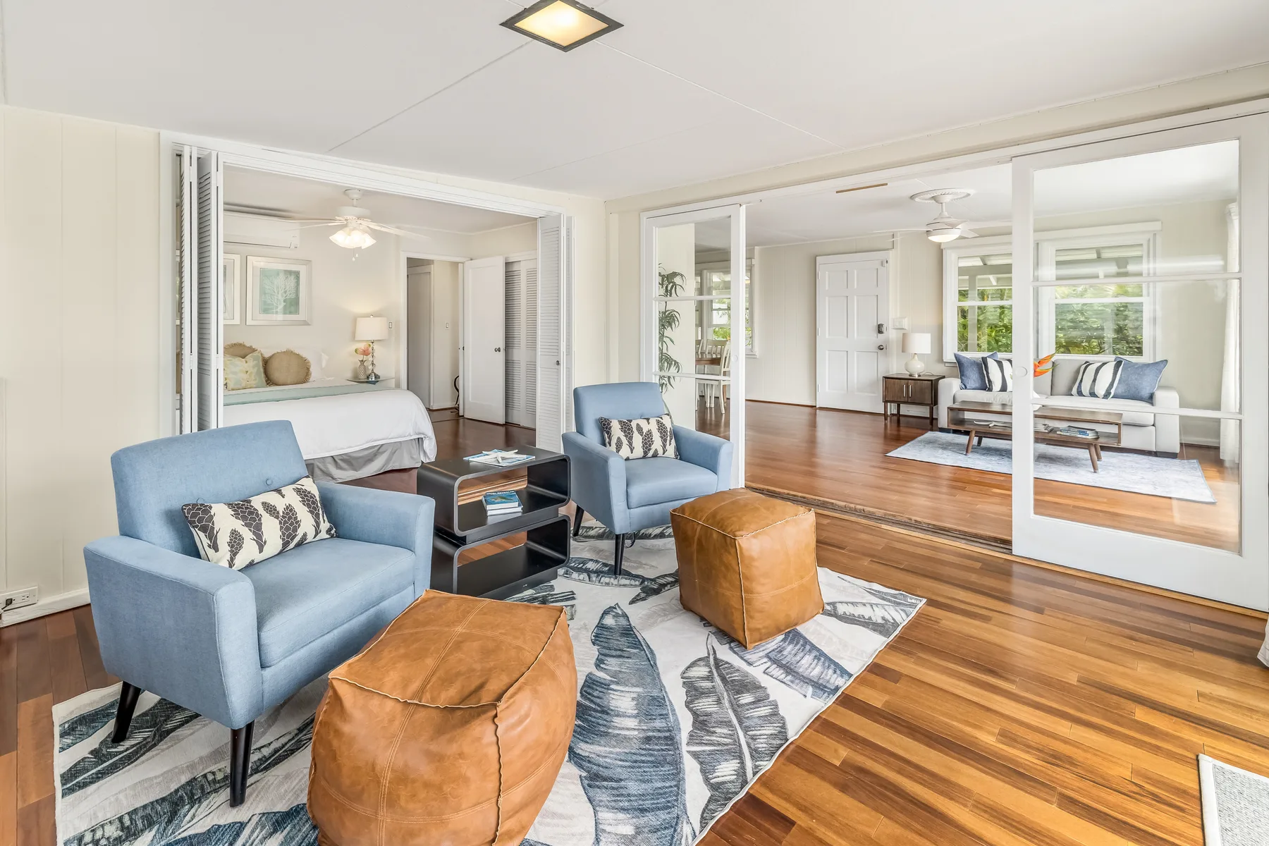 A bright living room with blue seating, a patterned rug, and hardwood flooring.