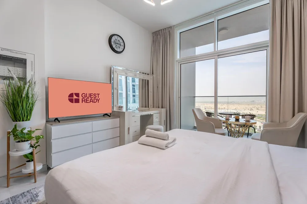 Un dormitorio luminoso con una cama bien arreglada junto a una ventana grande.