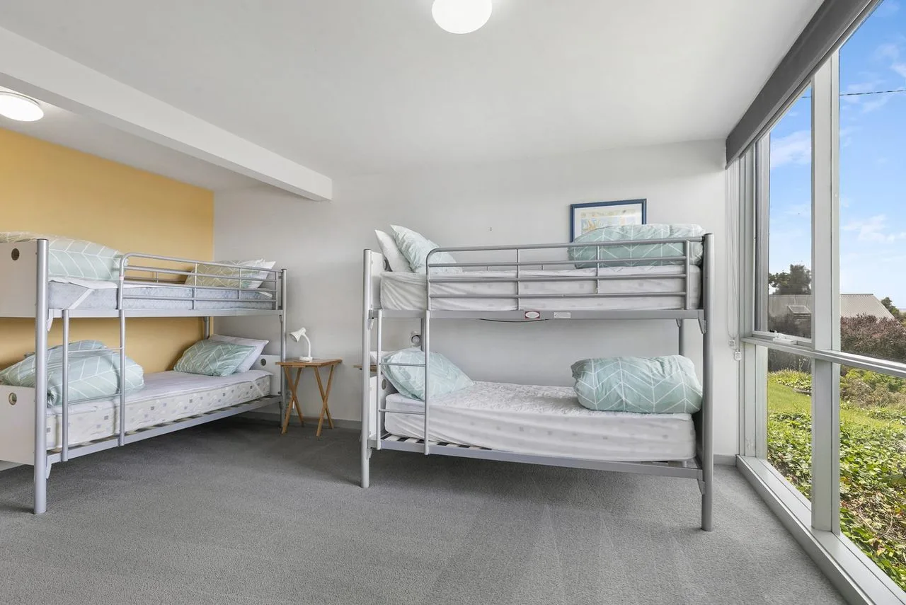 Un dormitorio luminoso con dos literas junto a grandes ventanas.