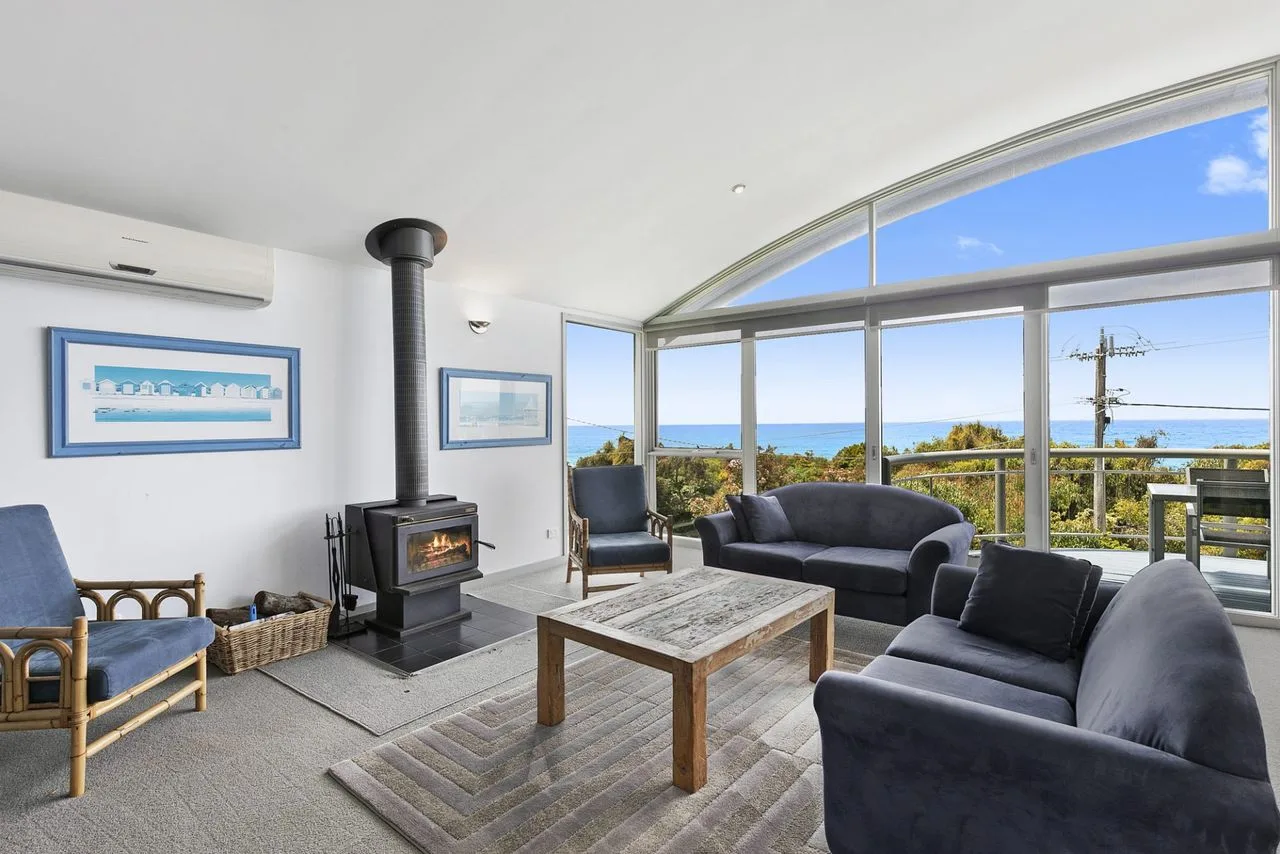 A living room with seating arranged around a coffee table and a large window.