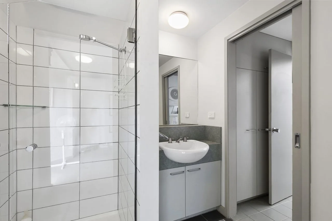 Un baño con una ducha de vidrio y un lavabo con mueble.